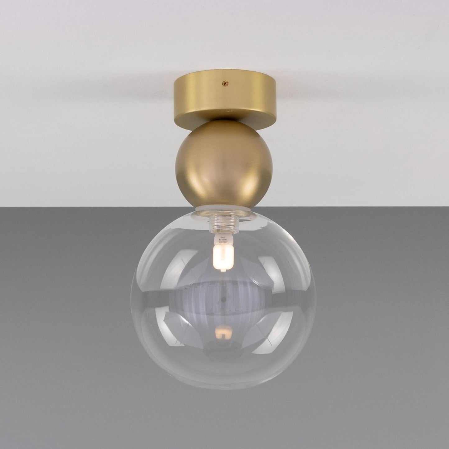 Helena Ceiling Lamp by Mullan Lighting with a minimalist brass sphere and 15cm glass globe shade, available in clear or frosted glass for modern interiors