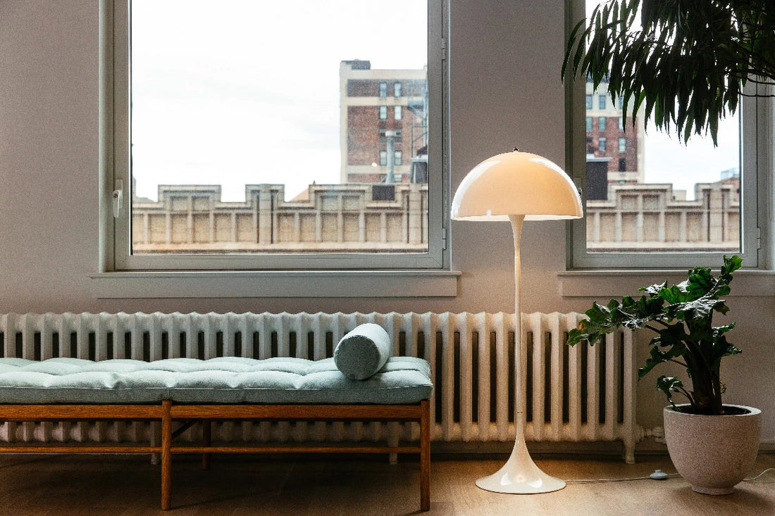 Louis-poulsen_carl-hansen-placed besides a planter in a room with two windows behind and a seating   