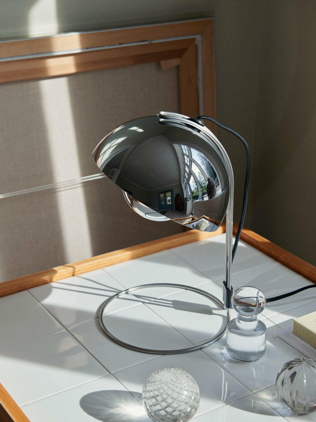Flowerpot VP4 Table Lamp by &Tradition in chrome finish, featuring its signature curved shade and adjustable base on a contemporary side table.