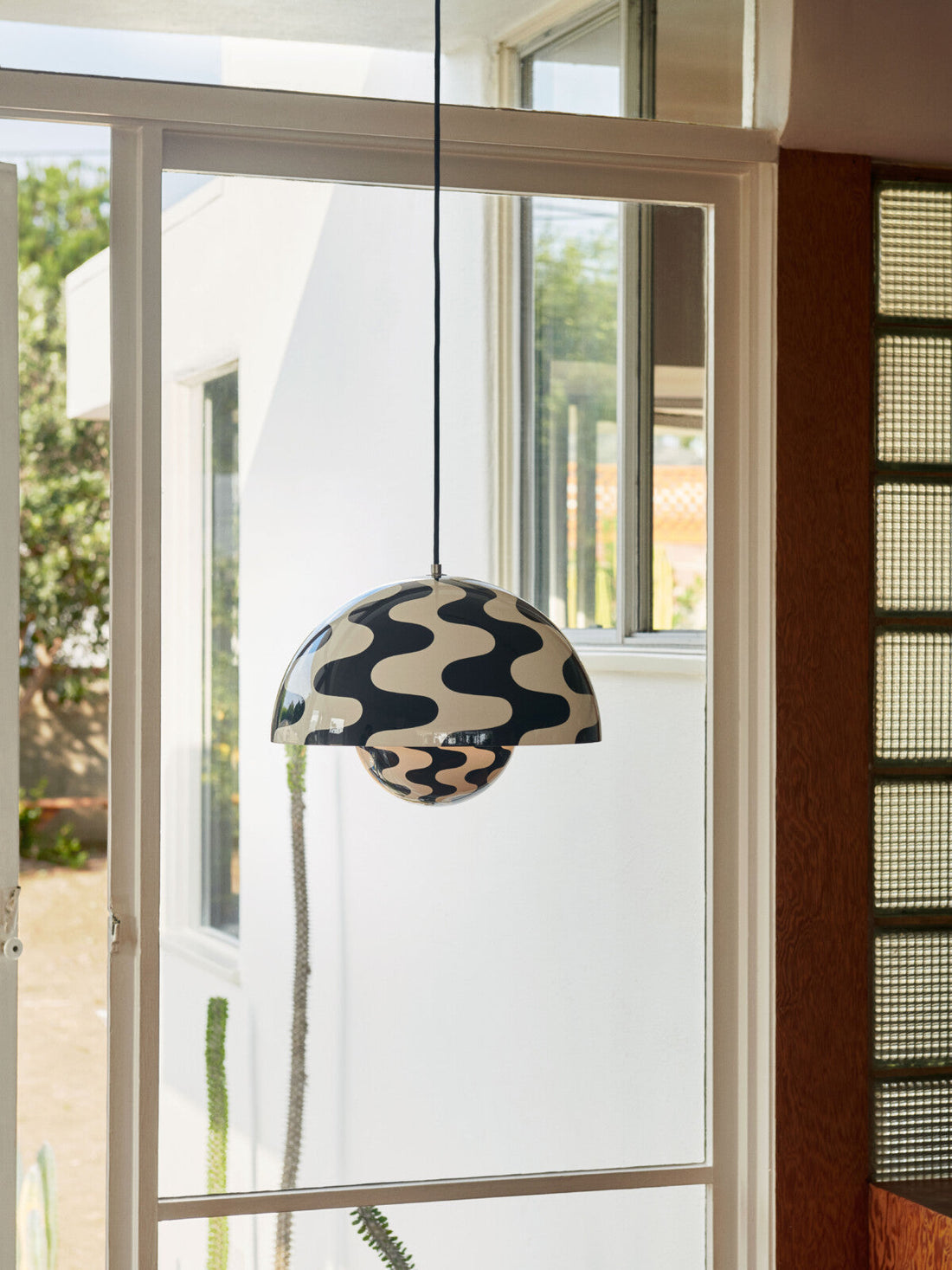 Flowerpot VP7 pendant lamp by &Tradition hanging above a kitchen island, glowing softly.