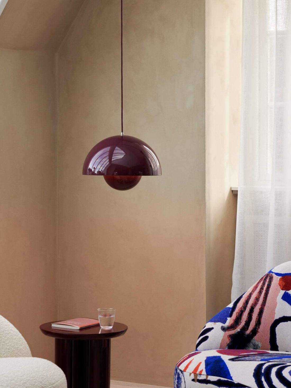 Flowerpot VP7 pendant lamp by &Tradition hanging above a kitchen island, glowing softly.