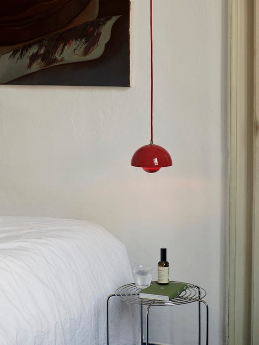 Flowerpot VP10 pendant lamp by &Tradition hanging above a side table, radiating soft light.