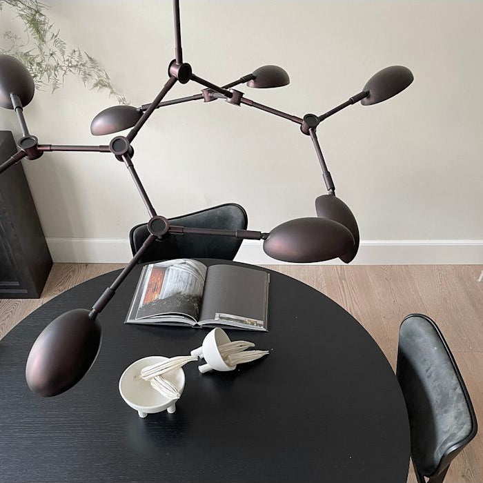 Drop Chandelier positioned above a modern dining table, creating a dramatic focal point with warm ambient light