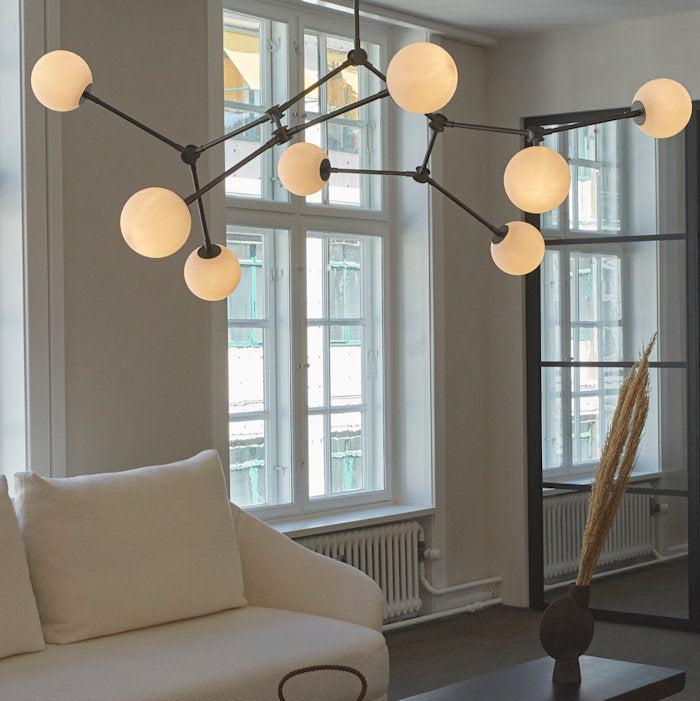 Modern living room featuring a perfectly proportioned chandelier with layered lighting creating a balanced and elegant interior ambiance.