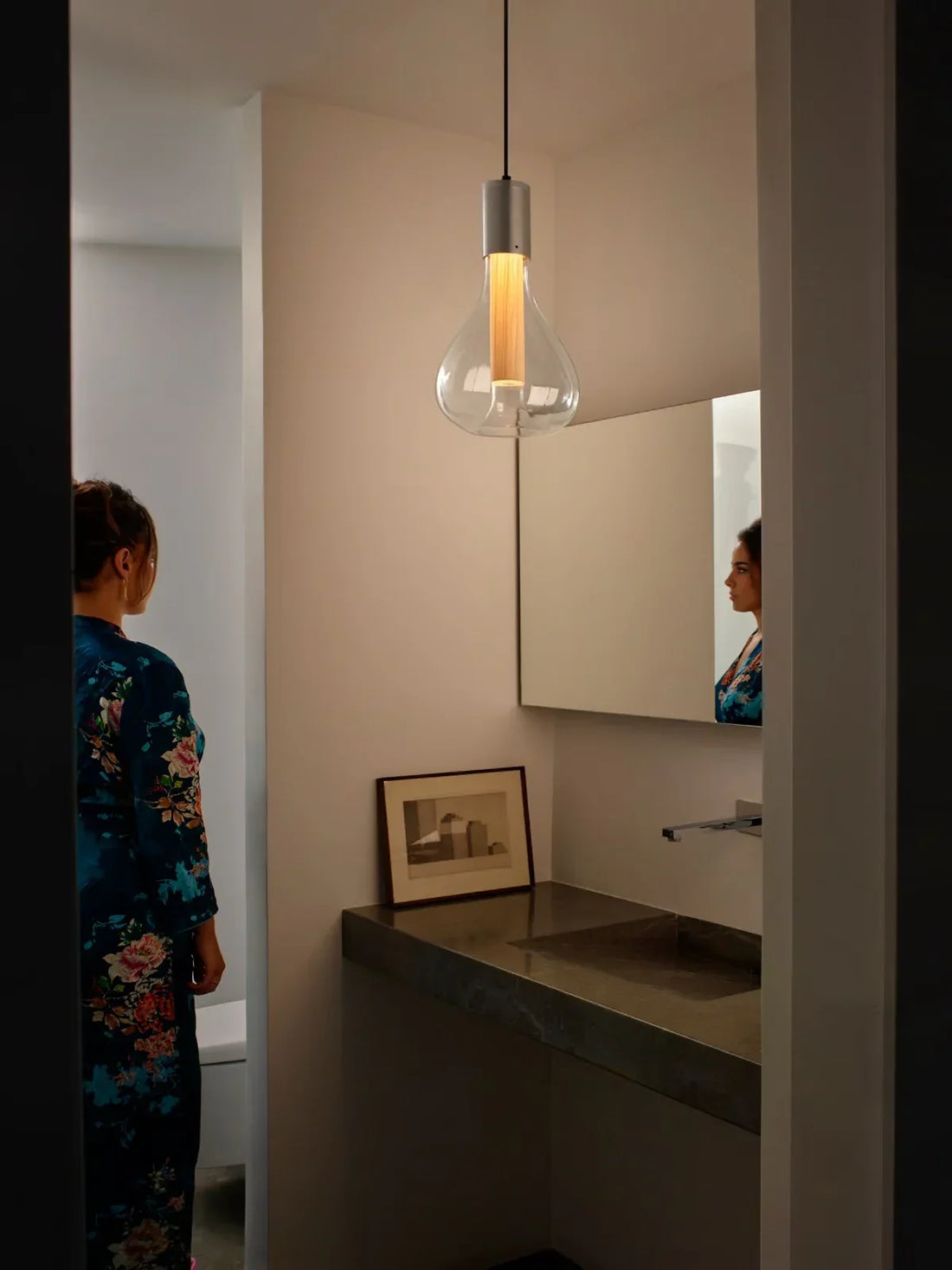 Decorative pendant light in a sophisticated modern bathroom above a vanity, paired with wall lighting and warm ambient illumination.
