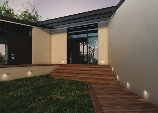 Elegant landscaped garden illuminated with warm uplights, pathway lights and accent lighting highlighting trees, sculptures, plants and architectural features.