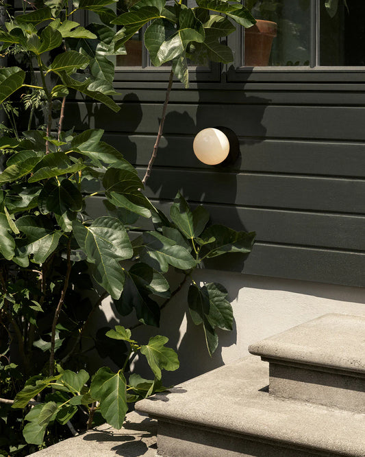 small round wall lamp placed outdoors besides stairs 