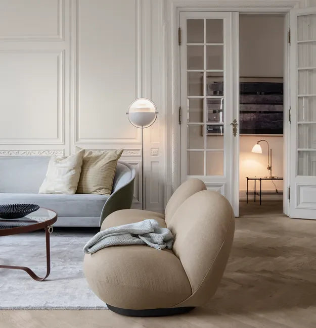 Warm Scandinavian-inspired living room illuminated with pendant lights, floor lamps, and ambient lighting during a rainy evening.