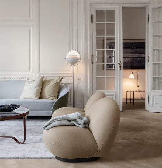 Warm Scandinavian-inspired living room illuminated with pendant lights, floor lamps, and ambient lighting during a rainy evening.
