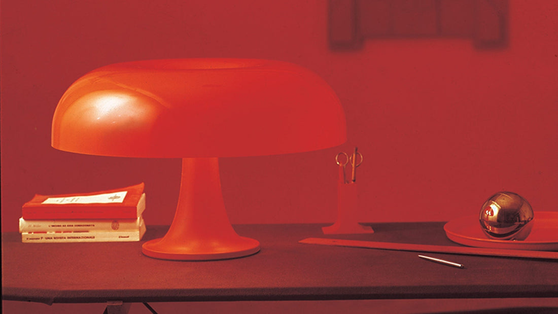 Alt Text: Nesso Lamp in bright orange placed on a side table, showcasing its mushroom-shaped silhouette and playful retro design.