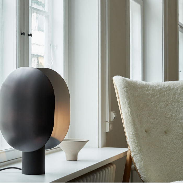 Clam Table Lamp by 101 Copenhagen styled on a side table in a Scandinavian-inspired living room with soft ambient lighting.
