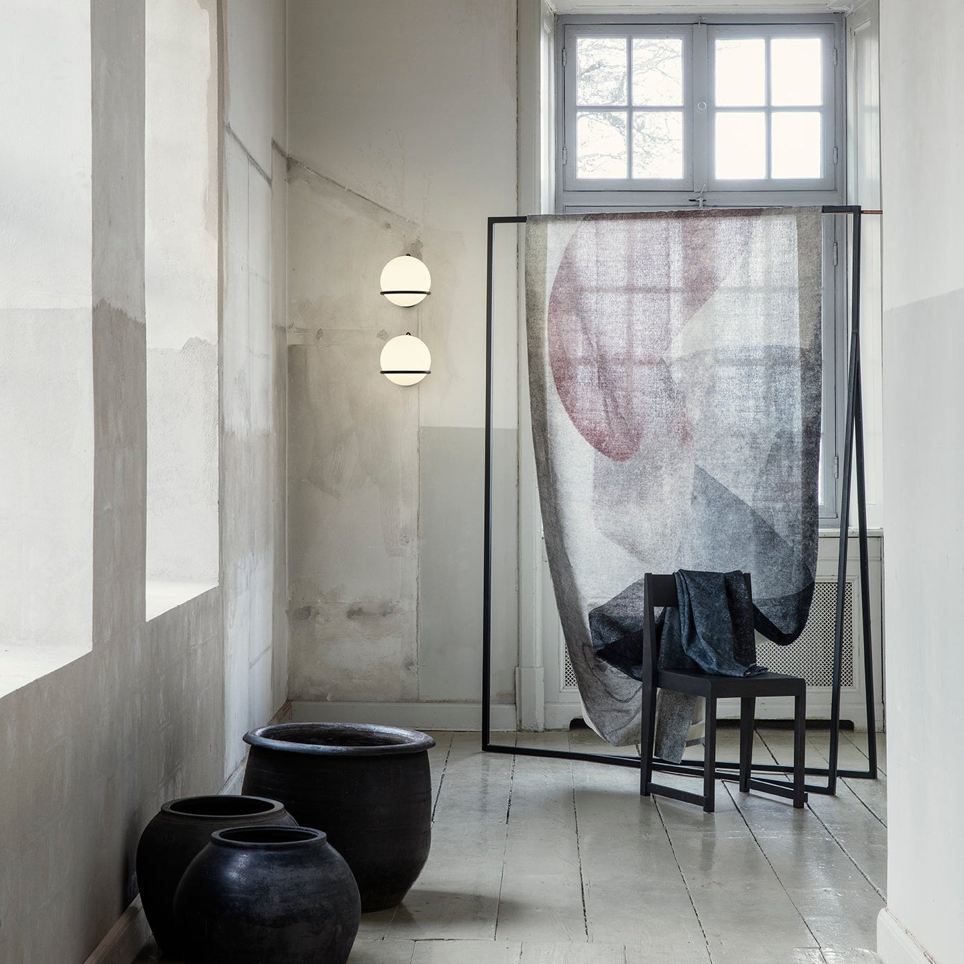 Modern interior with black vases, a chair, and a decorative screen in a room with large windows.


