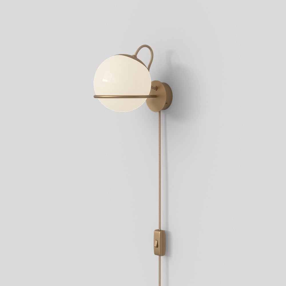 Wall-mounted lamp with a spherical glass shade and brass fixture on a light gray background


