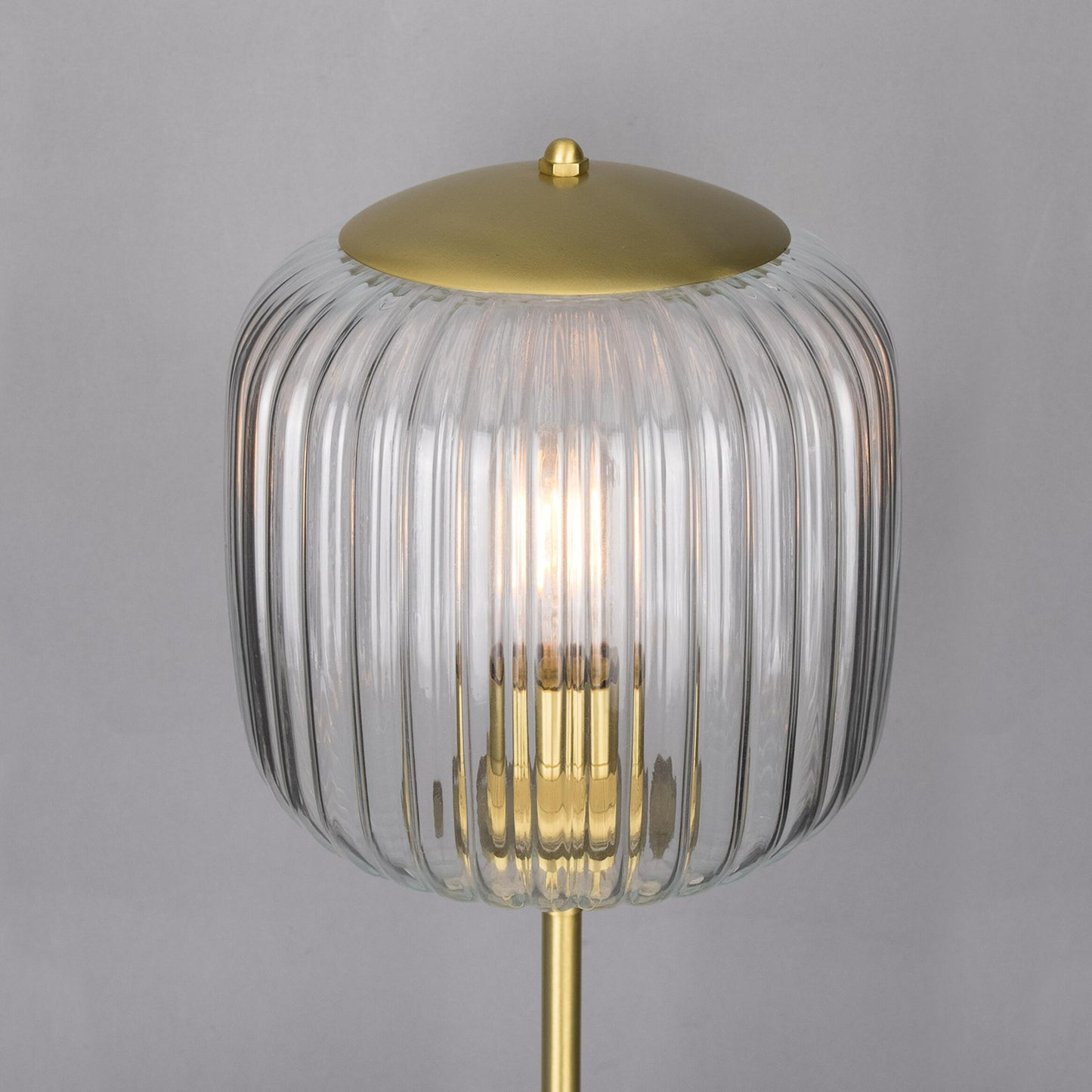 Decorative lamp with ribbed glass shade and gold base on a gray background