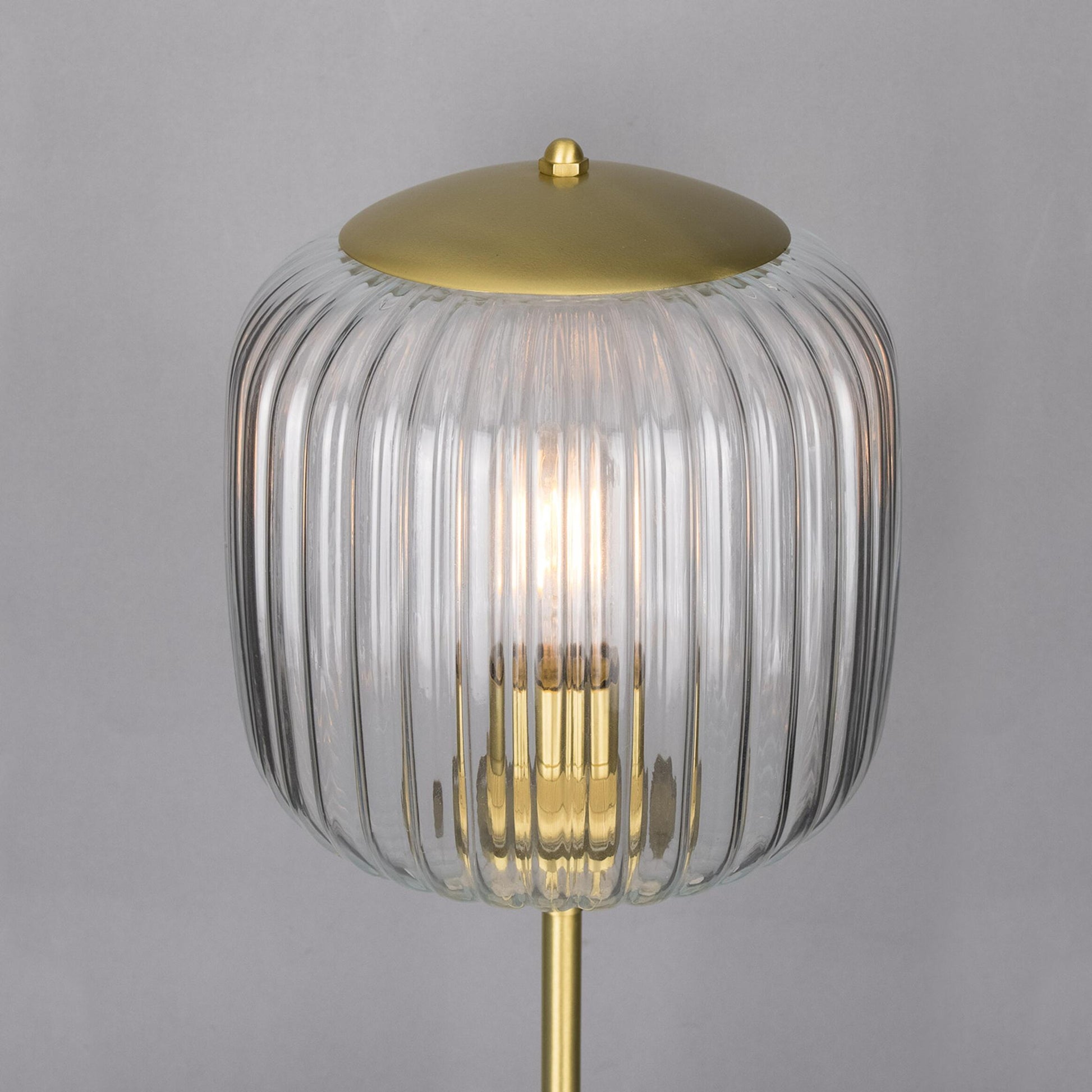 Decorative lamp with ribbed glass shade and gold base on a gray background
