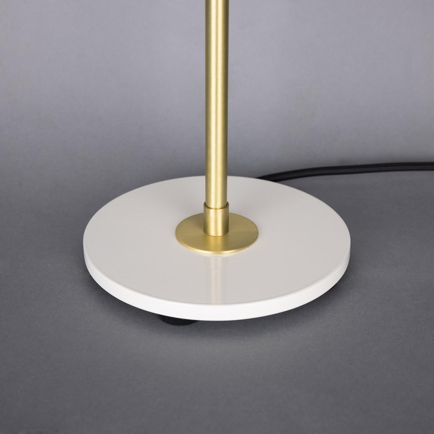 Table lamp with gold stem and white base on a gray background