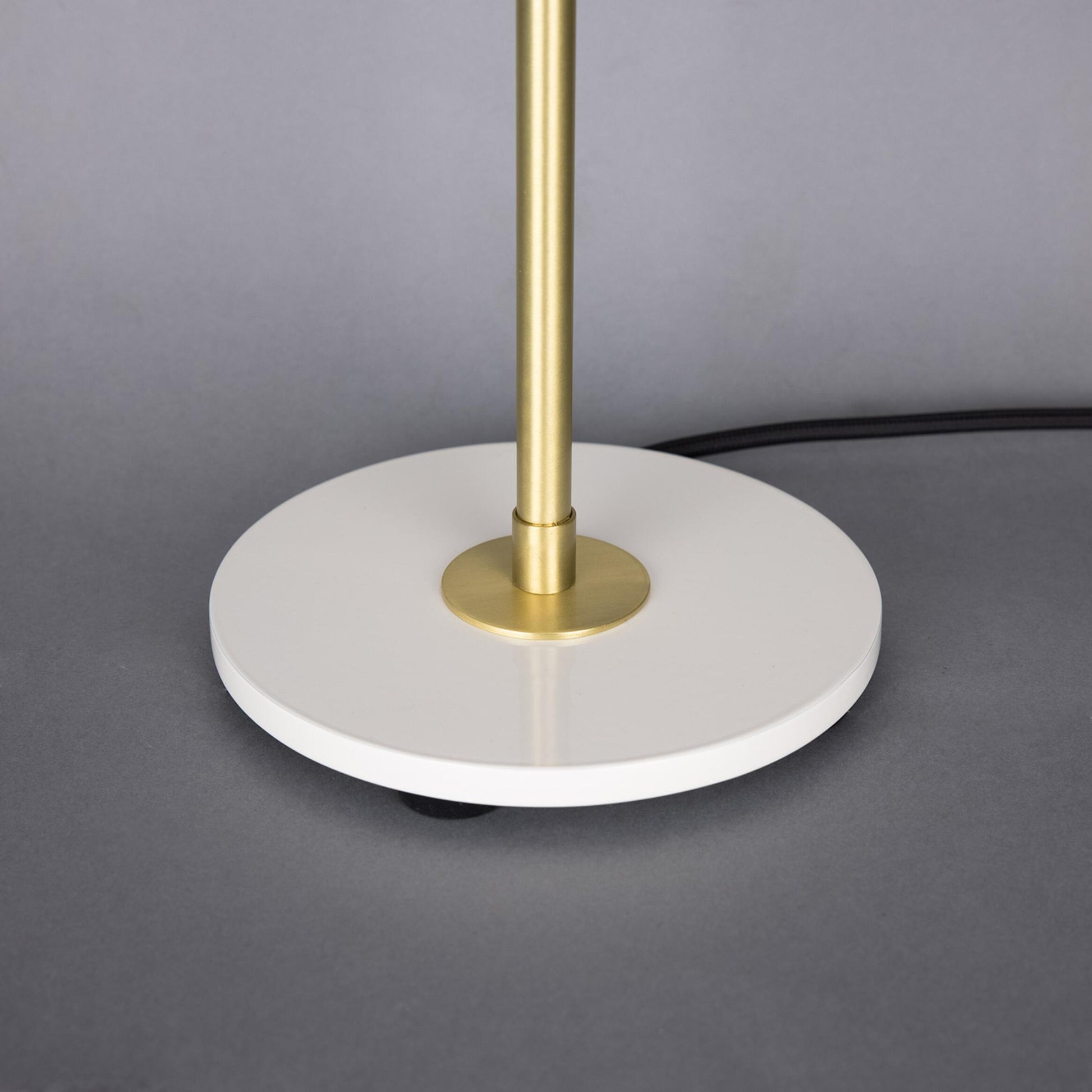Table lamp with gold stem and white base on a gray background