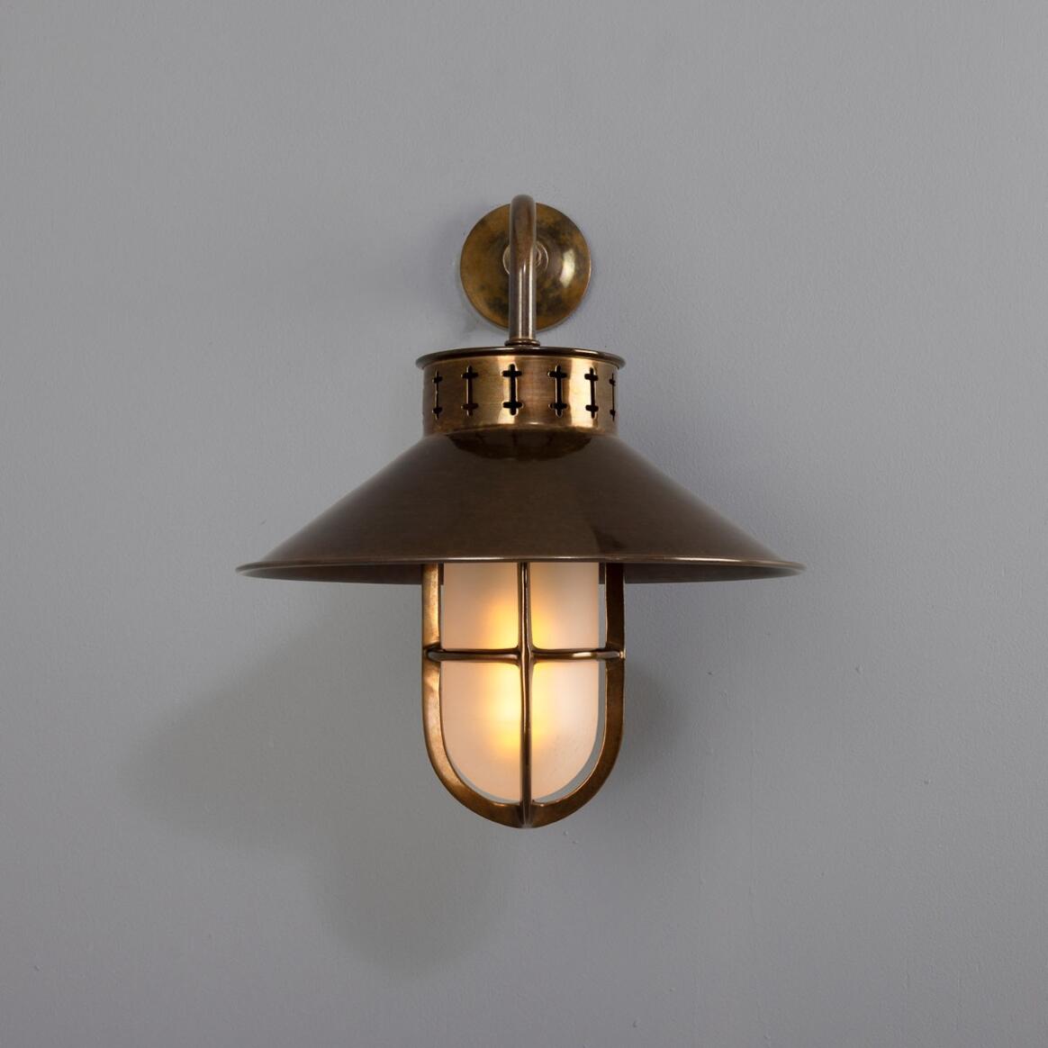 Bronze wall-mounted lantern with glass cover on a gray background
