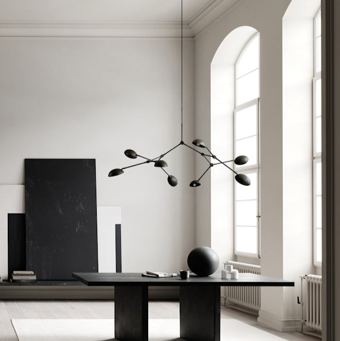 Drop Chandelier positioned above a modern dining table, creating a dramatic focal point with warm ambient light