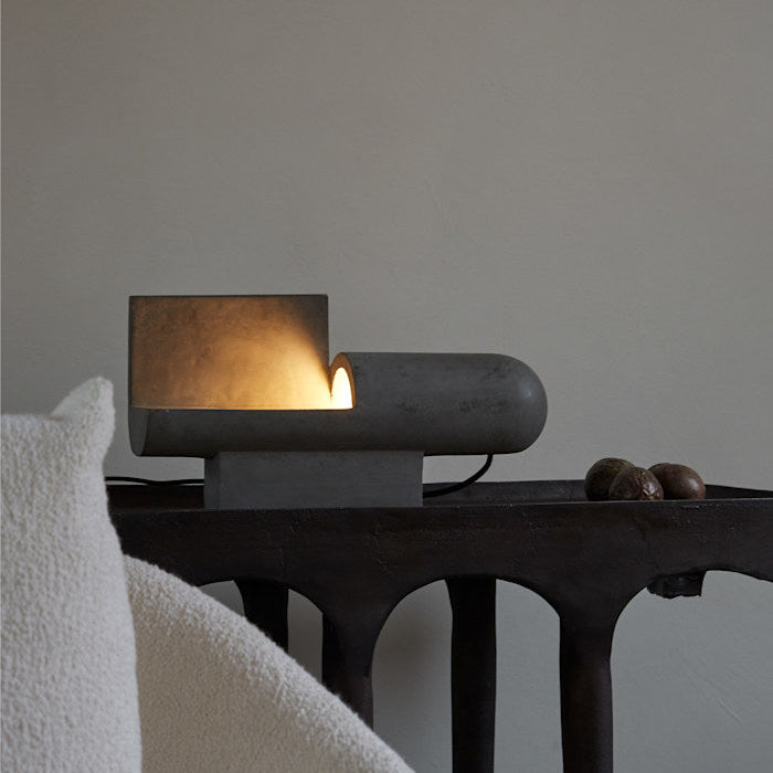 Brutalist Lamp by 101 Copenhagen glowing warmly in a dim room, highlighting its raw surface and moody ambiance