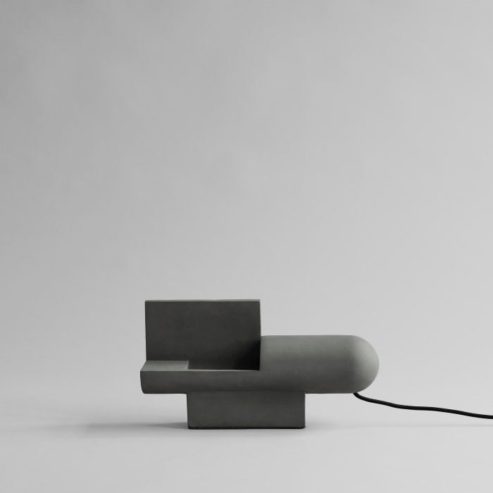 Brutalist Lamp by 101 Copenhagen with its raw textured surface and geometric form placed on a console in a modern setting.