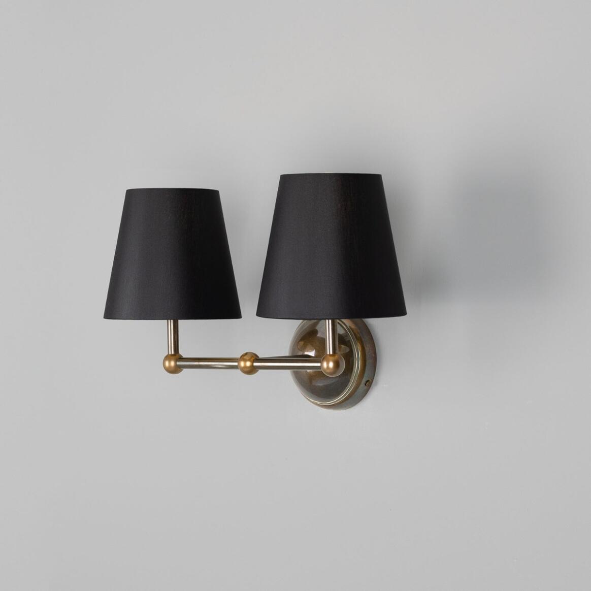 Wall-mounted lamp with two black lampshades and gold fixtures on a gray background