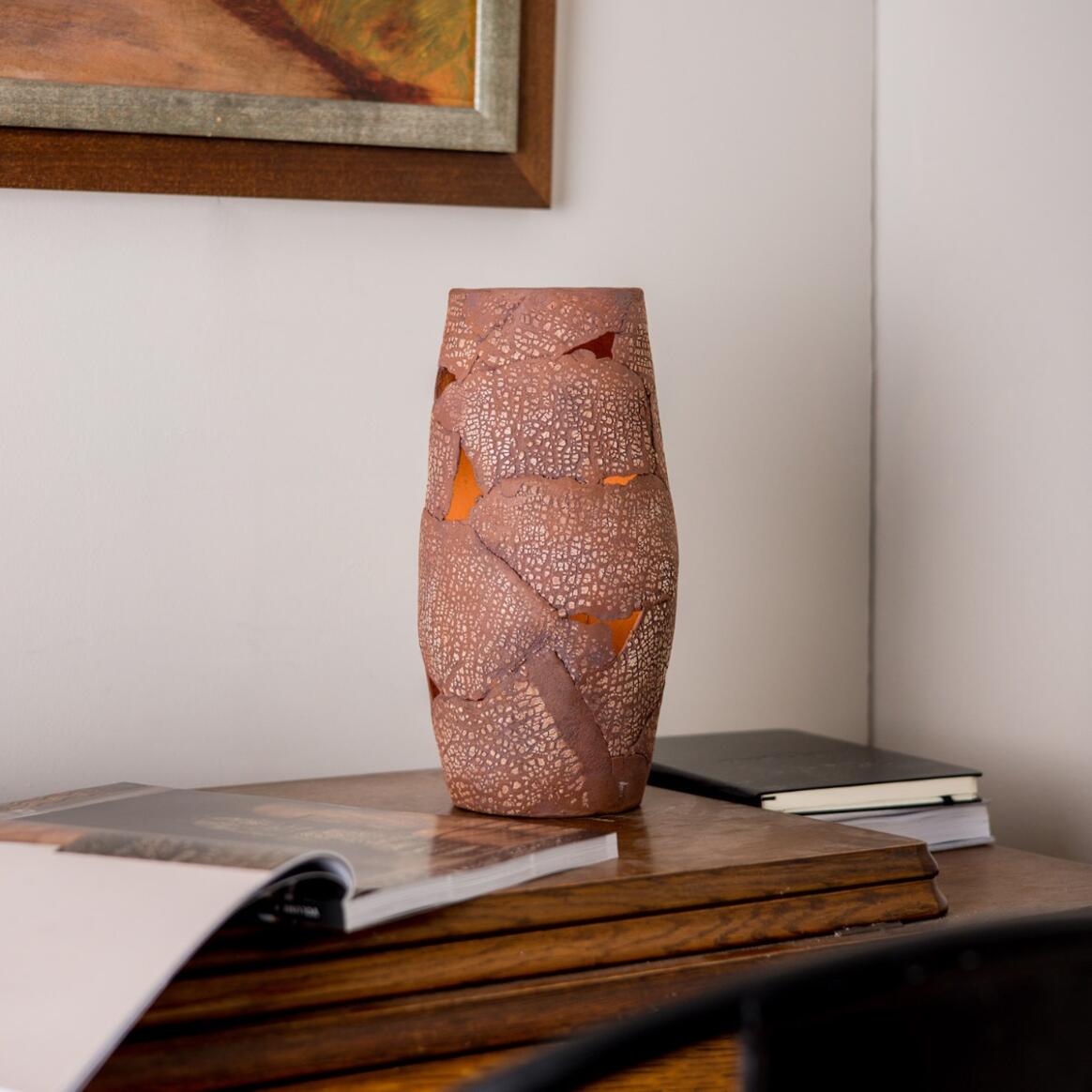 Decorative vase on a wooden surface with books and a framed picture in the background