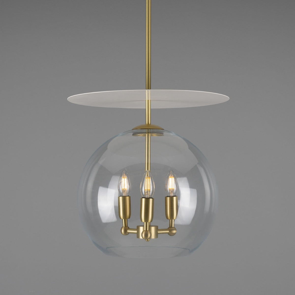 Modern pendant light with glass shade and gold fixture on a gray background