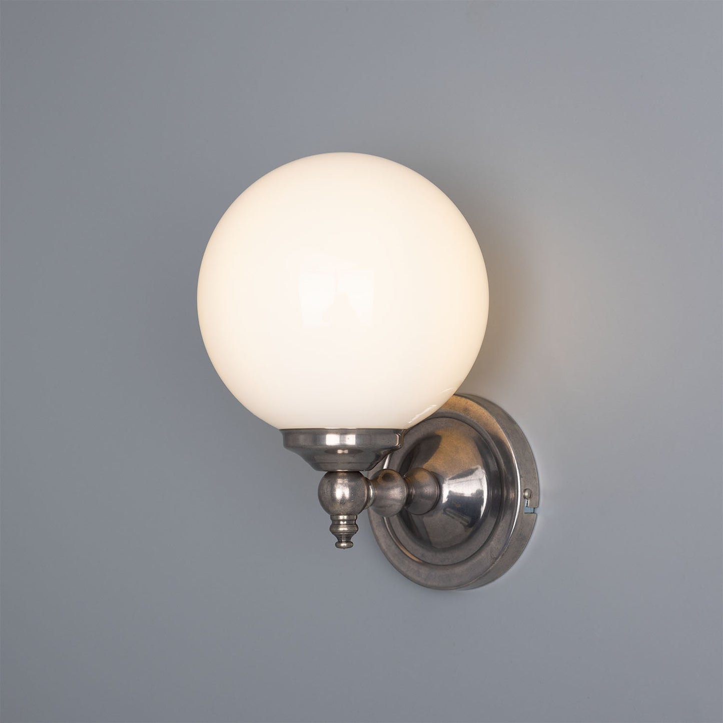 Wall-mounted light fixture with a round glass shade on a gray background