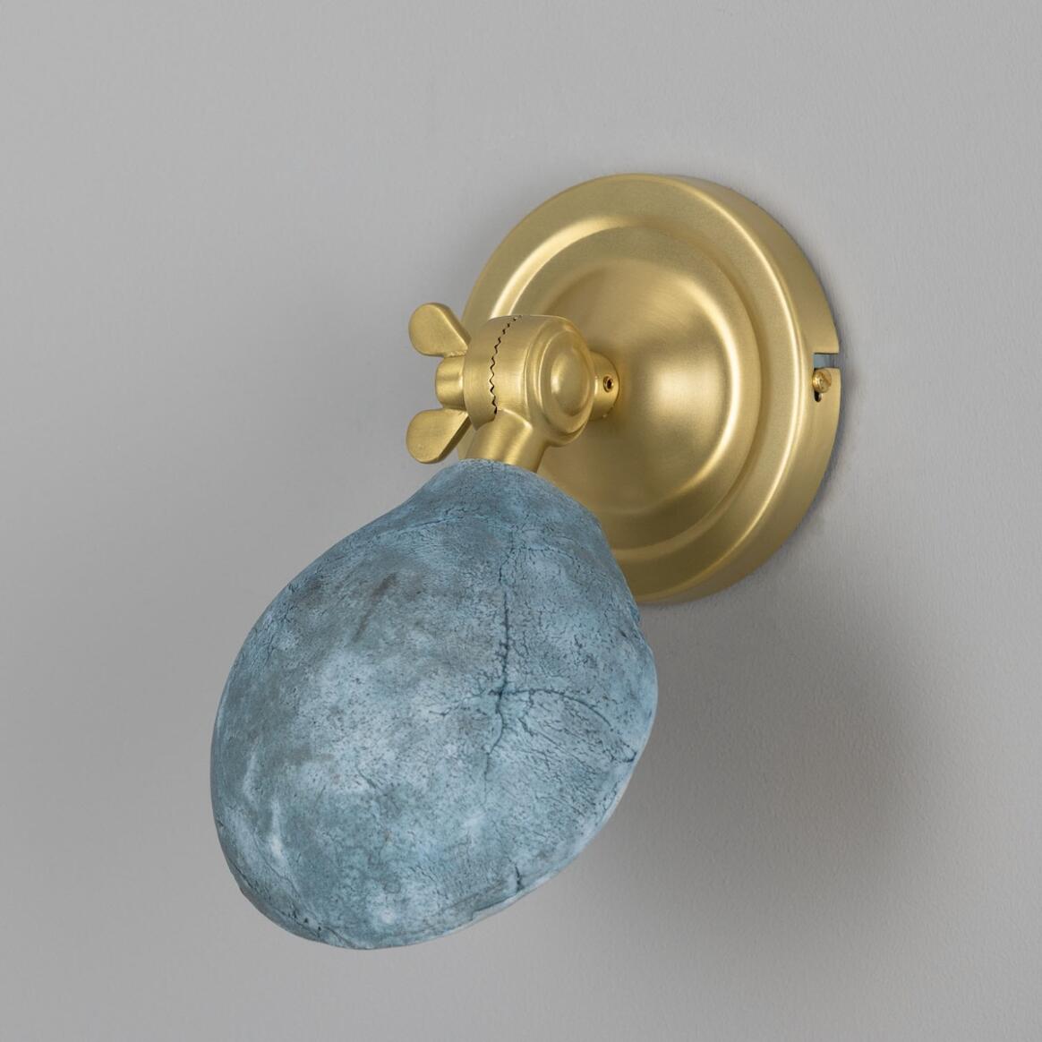 Decorative wall sconce with blue stone finish and gold metal fixture on a gray background