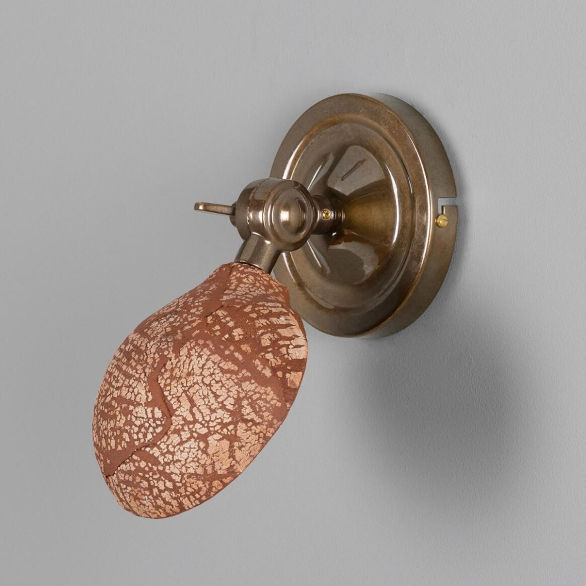 Wall-mounted light fixture with a textured brown glass shade on a gray background