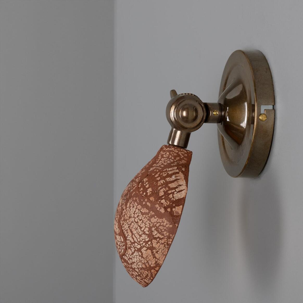 Decorative wall light fixture with a brown leaf-like design on a gray background