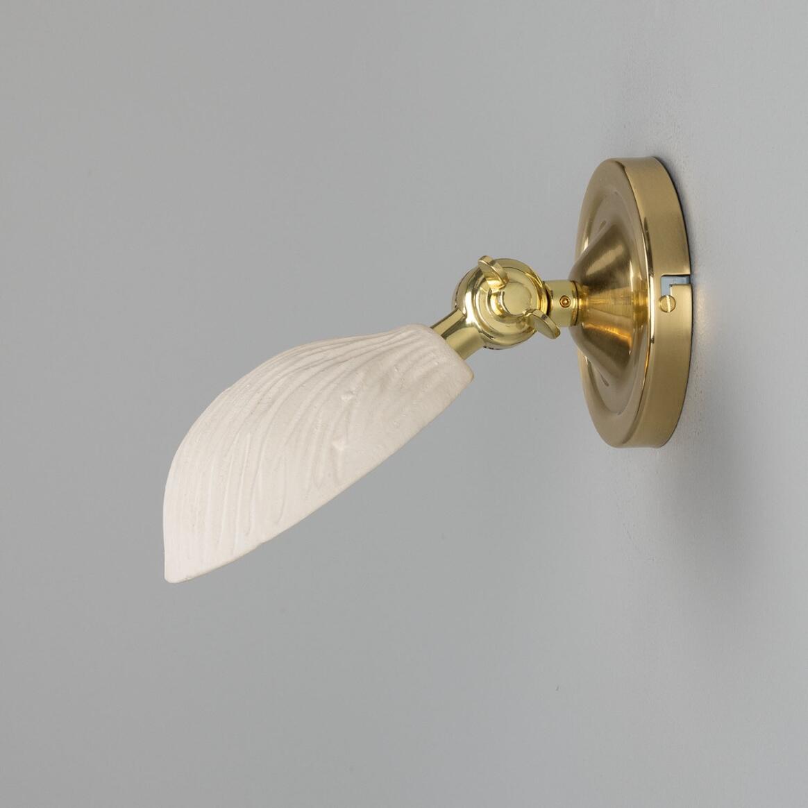 Wall-mounted light fixture with gold finish and white glass shade on a gray background