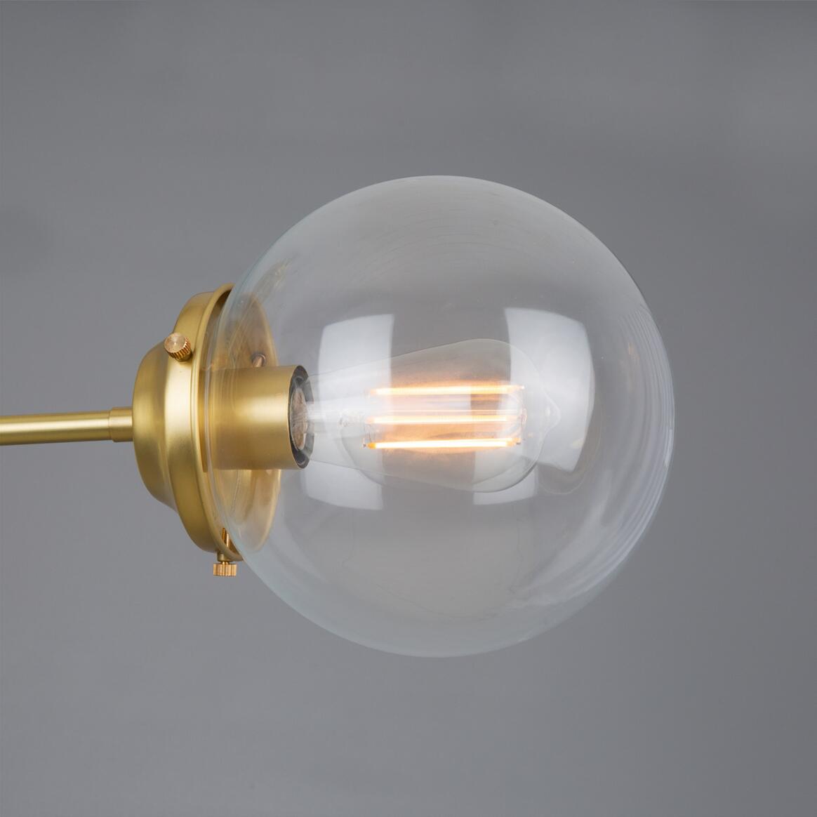 Clear glass light bulb with gold fixture on a gray background