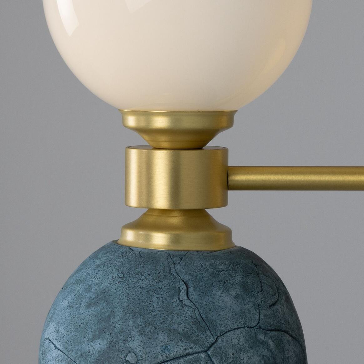 Close-up of a lamp with a gold fixture and blue base on a gray background