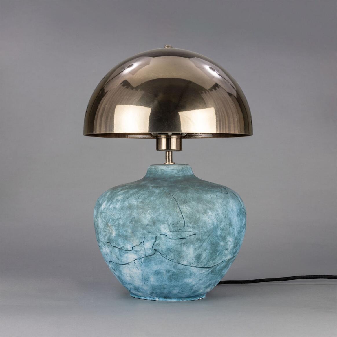 Table lamp with a metallic dome shade and textured blue base on a gray background