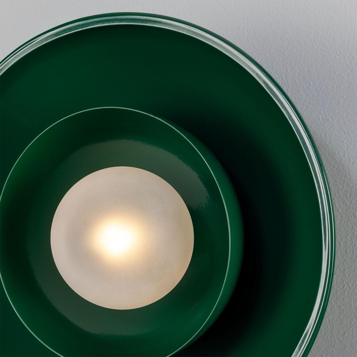 Close-up of a green circular light fixture with a white bulb on a gray background
