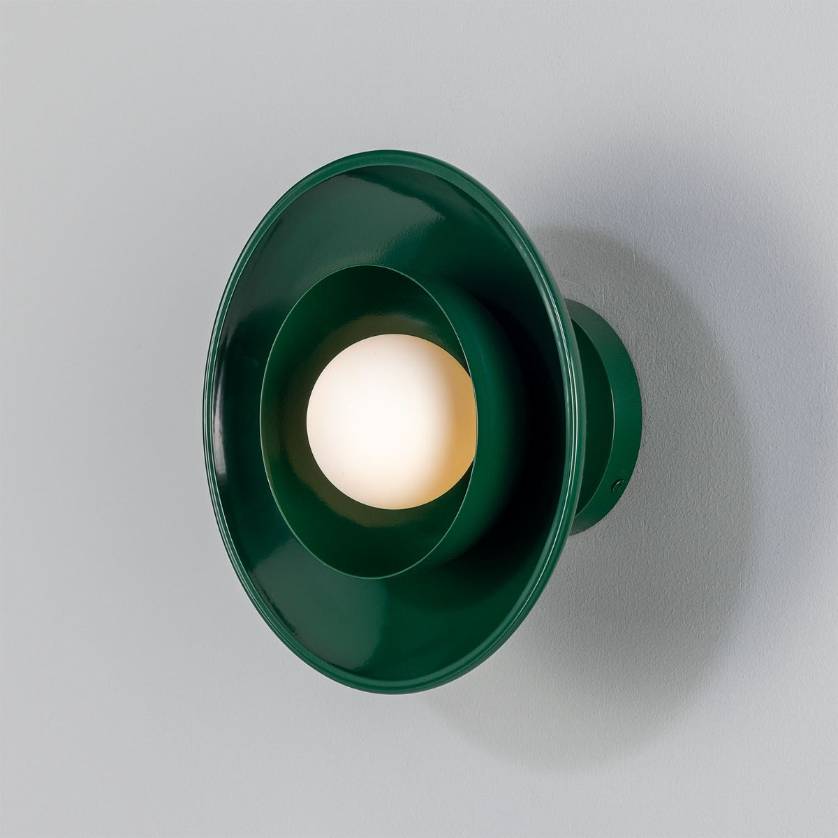 Green wall sconce with a light bulb on a gray background