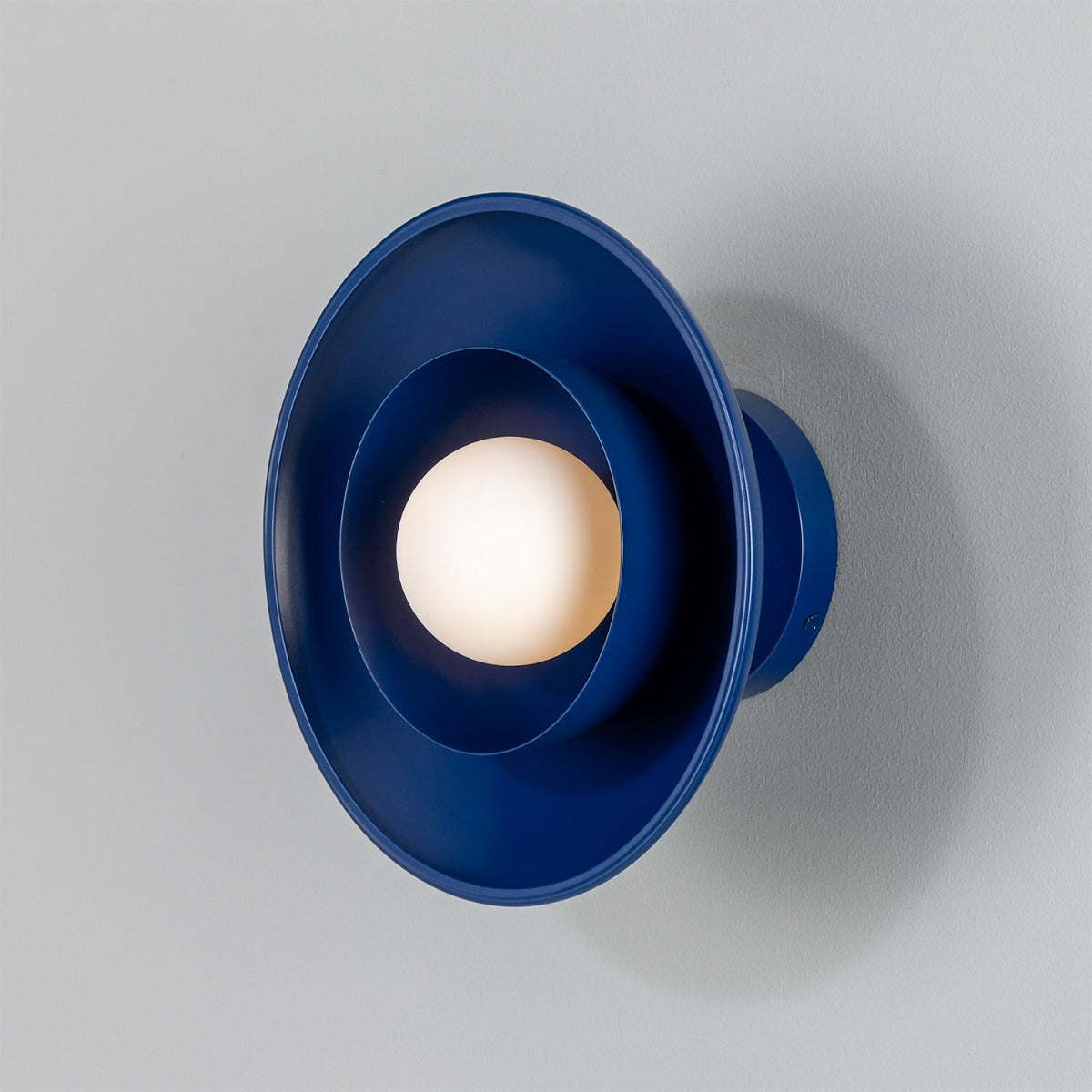 Blue wall sconce with a white bulb on a gray background