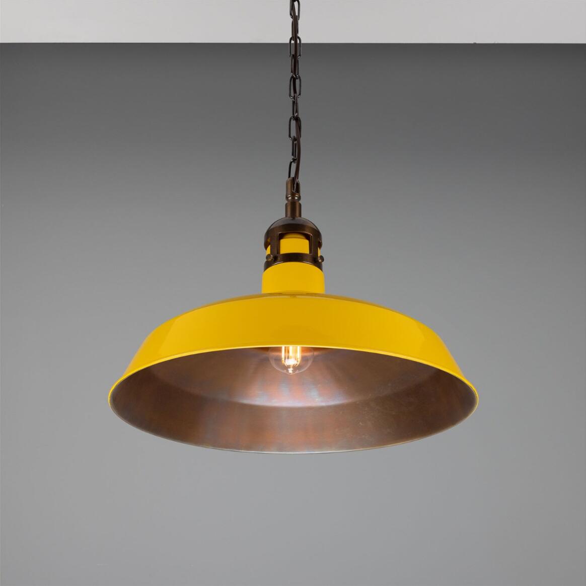Yellow pendant light with a metallic finish on a gray background