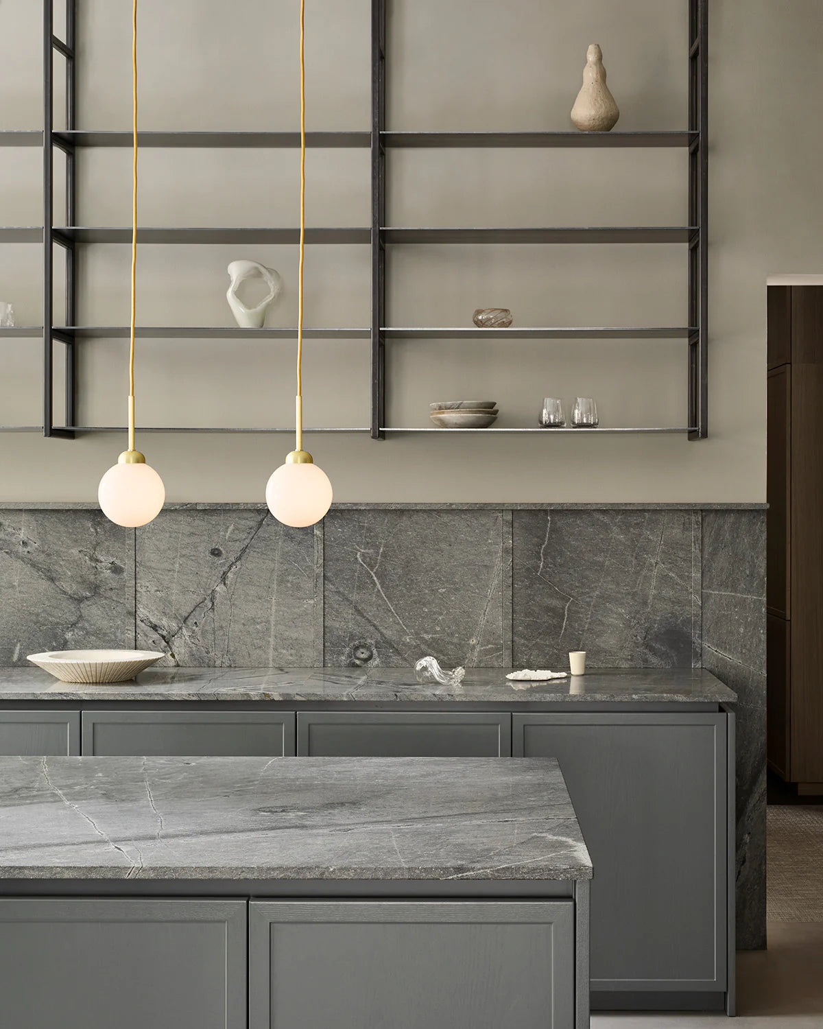 Nuura Apiales 1 hanging lamp with gold fabric cord and warm, soft glow from its opal white glass shade.