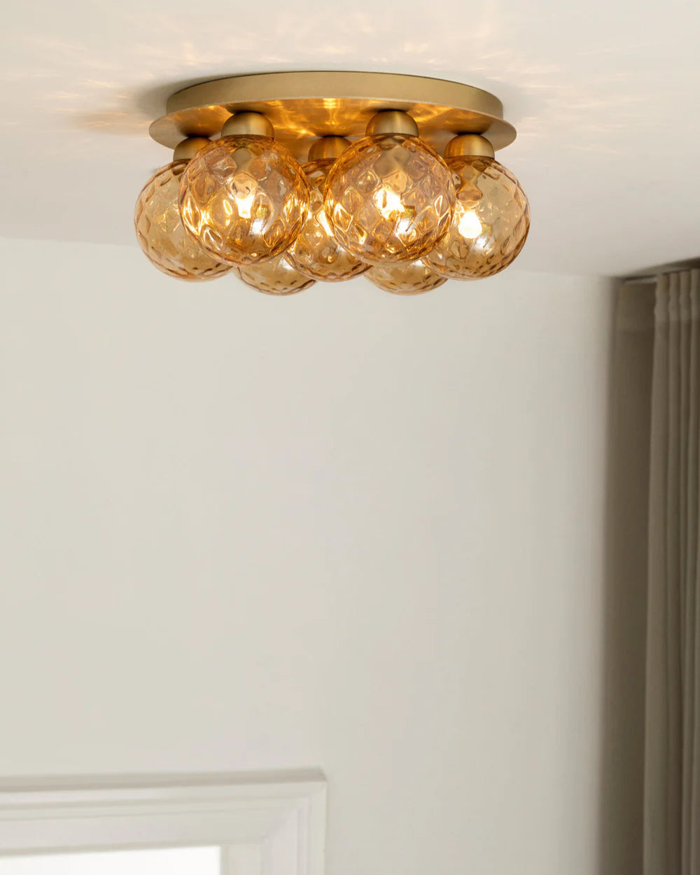 Apiales 7 Ceiling Lamp by Nuura – golden glass domes on round metal base.

