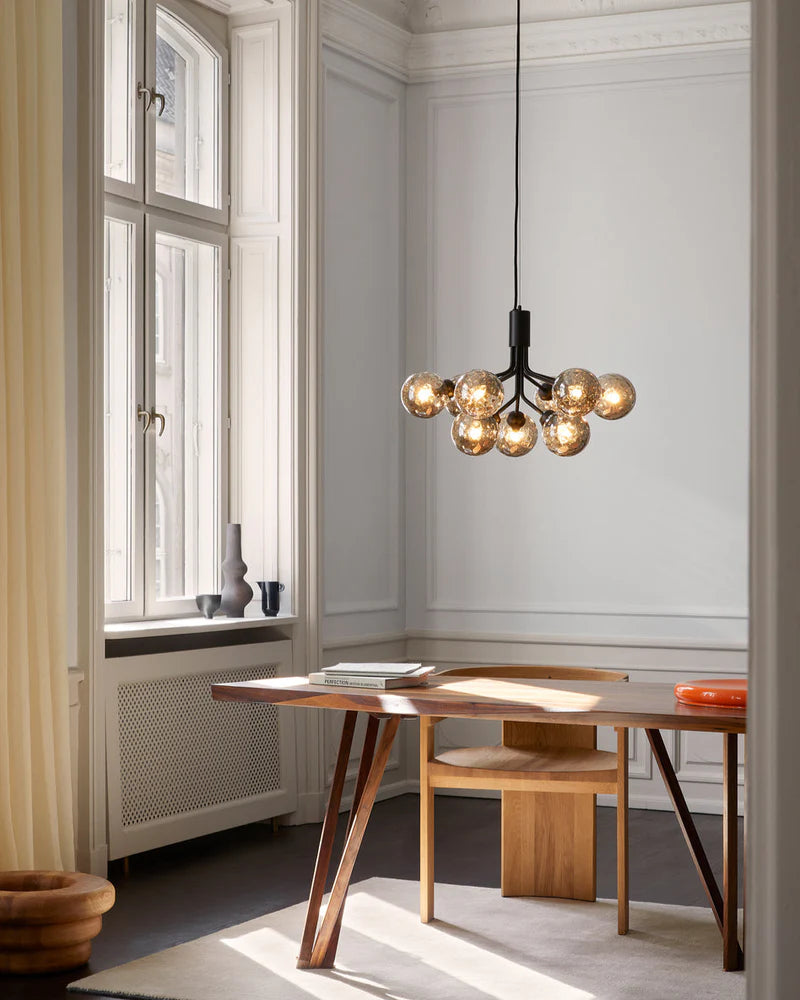 Nuura Apiales 9 chandelier with satin black arms and nine smoked glass shades, designed for modern interiors with elegant, ambient lighting.







