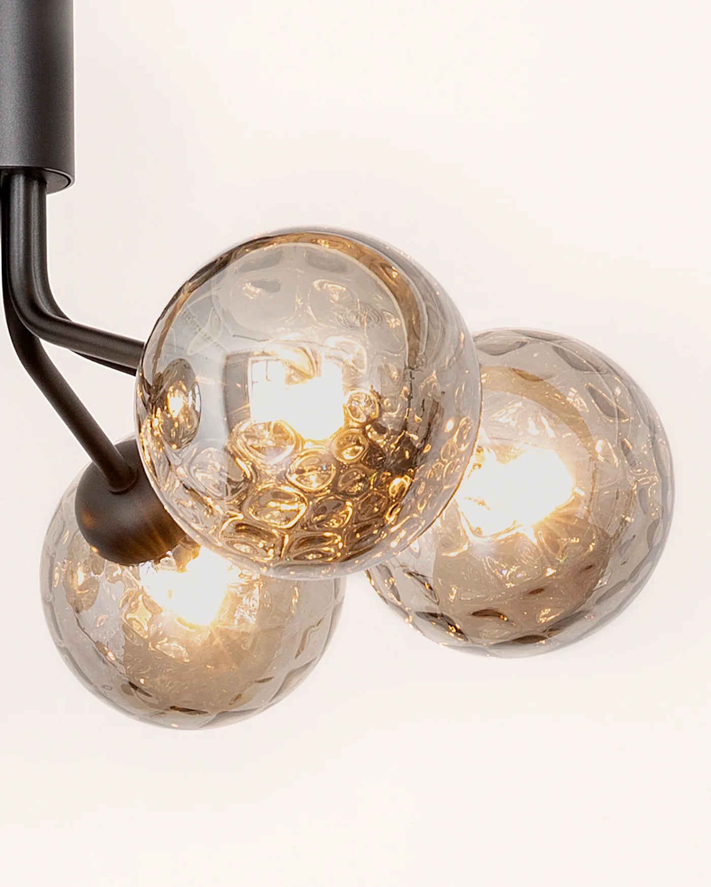 Modern ceiling chandelier from Nuura with patterned glass domes and matte black finish, suitable for stylish low-ceilinged rooms.

