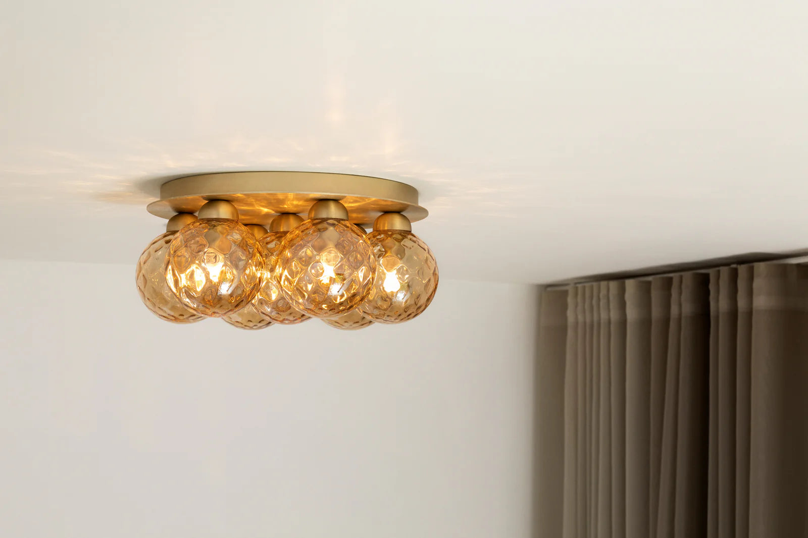 Apiales 7 Ceiling Lamp by Nuura – golden glass domes on round metal base.

