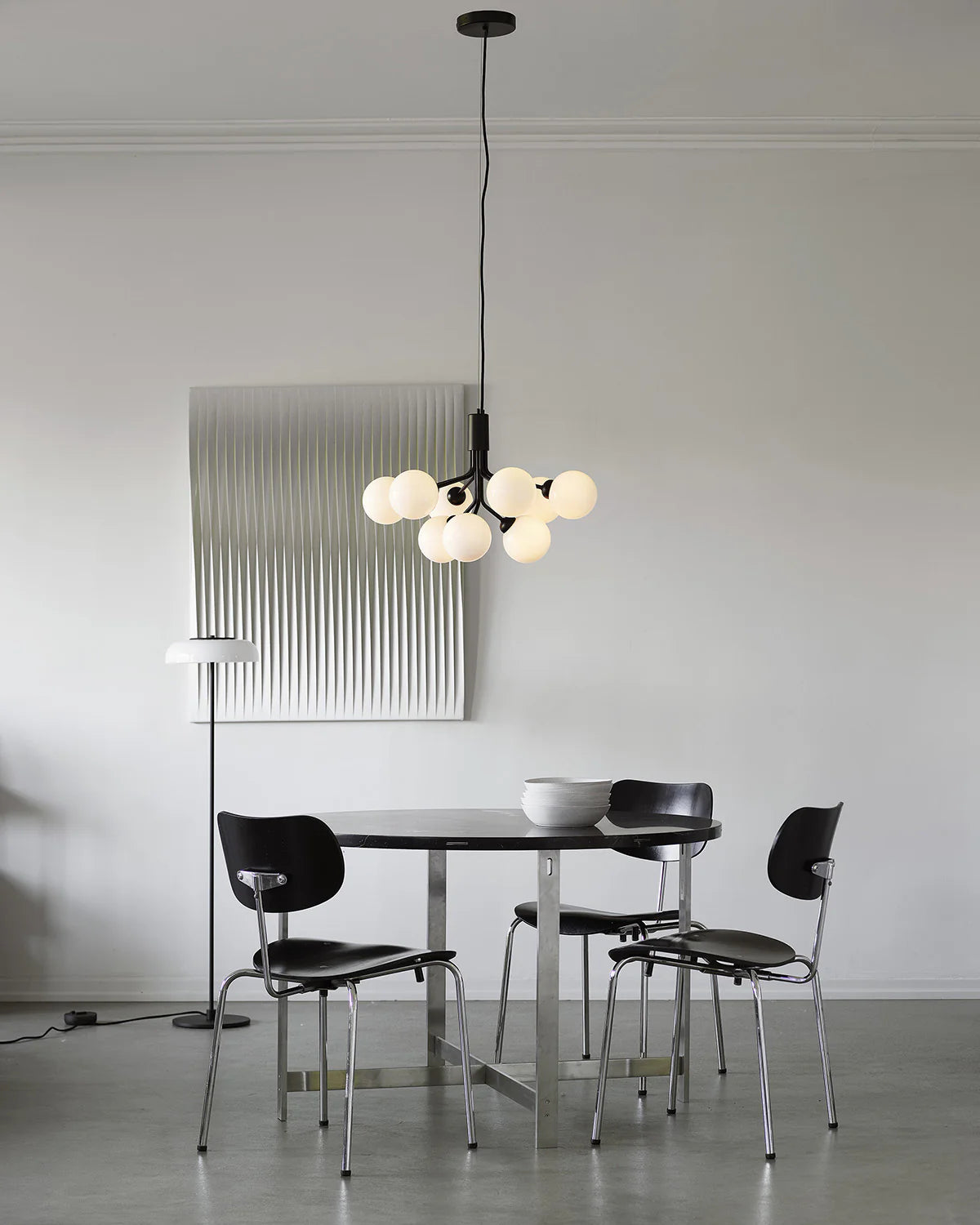 Nuura Apiales 9 chandelier with satin black arms and nine smoked glass shades, designed for modern interiors with elegant, ambient lighting.







