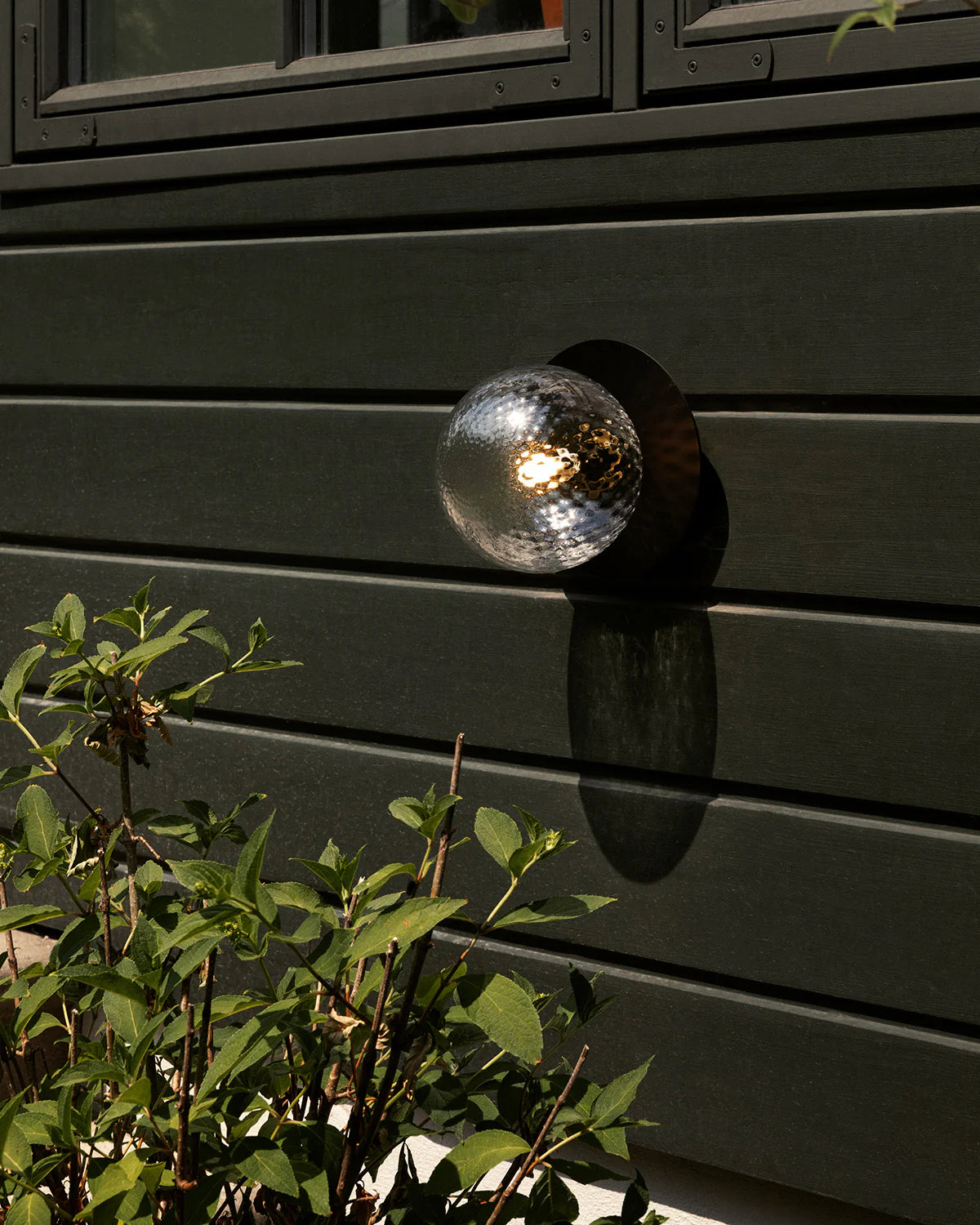 Nuura Liila 1 Outdoor Wall Lamp with bronze finish and clear glass globe, ideal for stylish outdoor wall or ceiling lighting in modern exterior spaces.