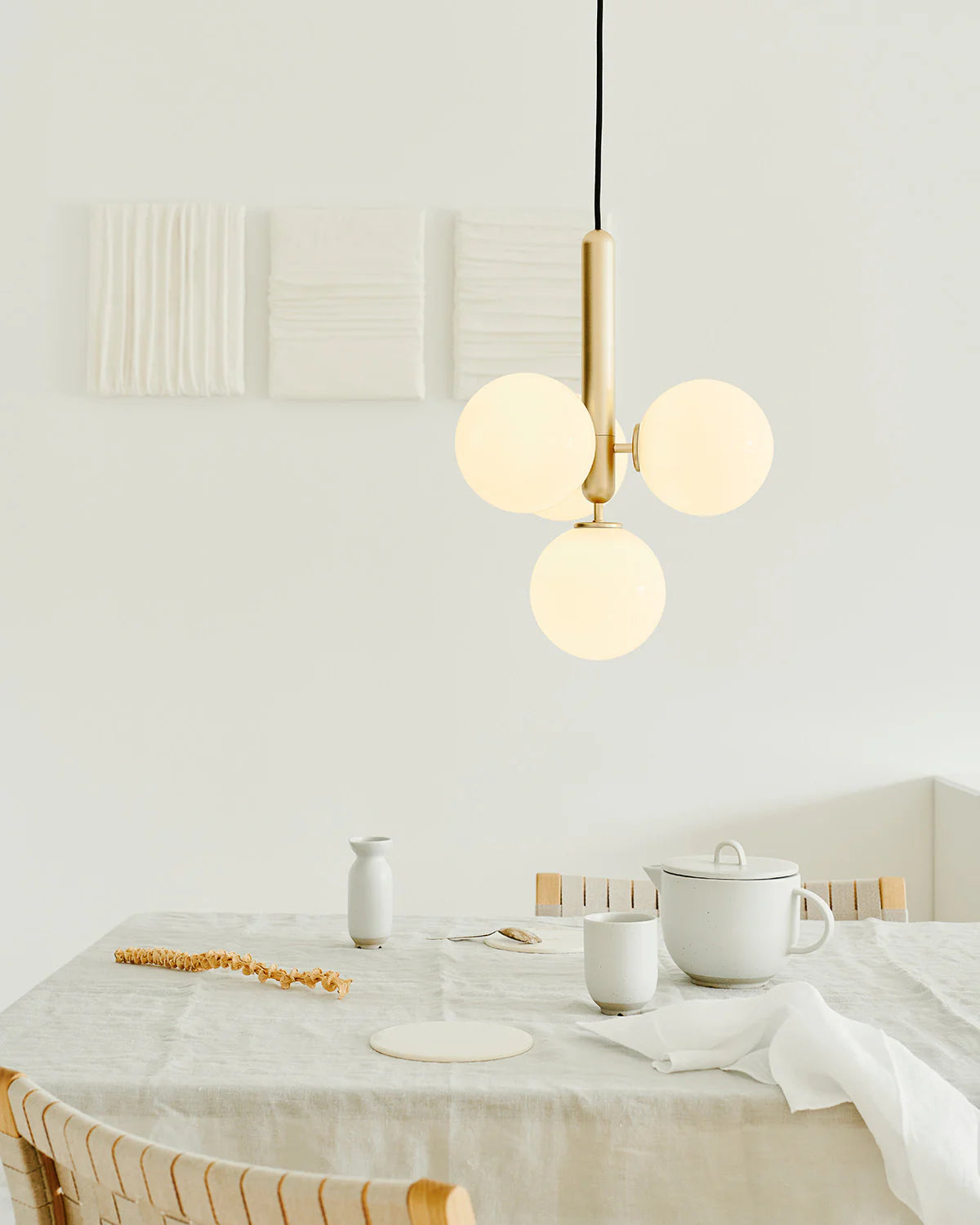 Four-light Scandinavian pendant lamp by Nuura, featuring brass frame and white glass shades for living room , dining room or kitchen lights