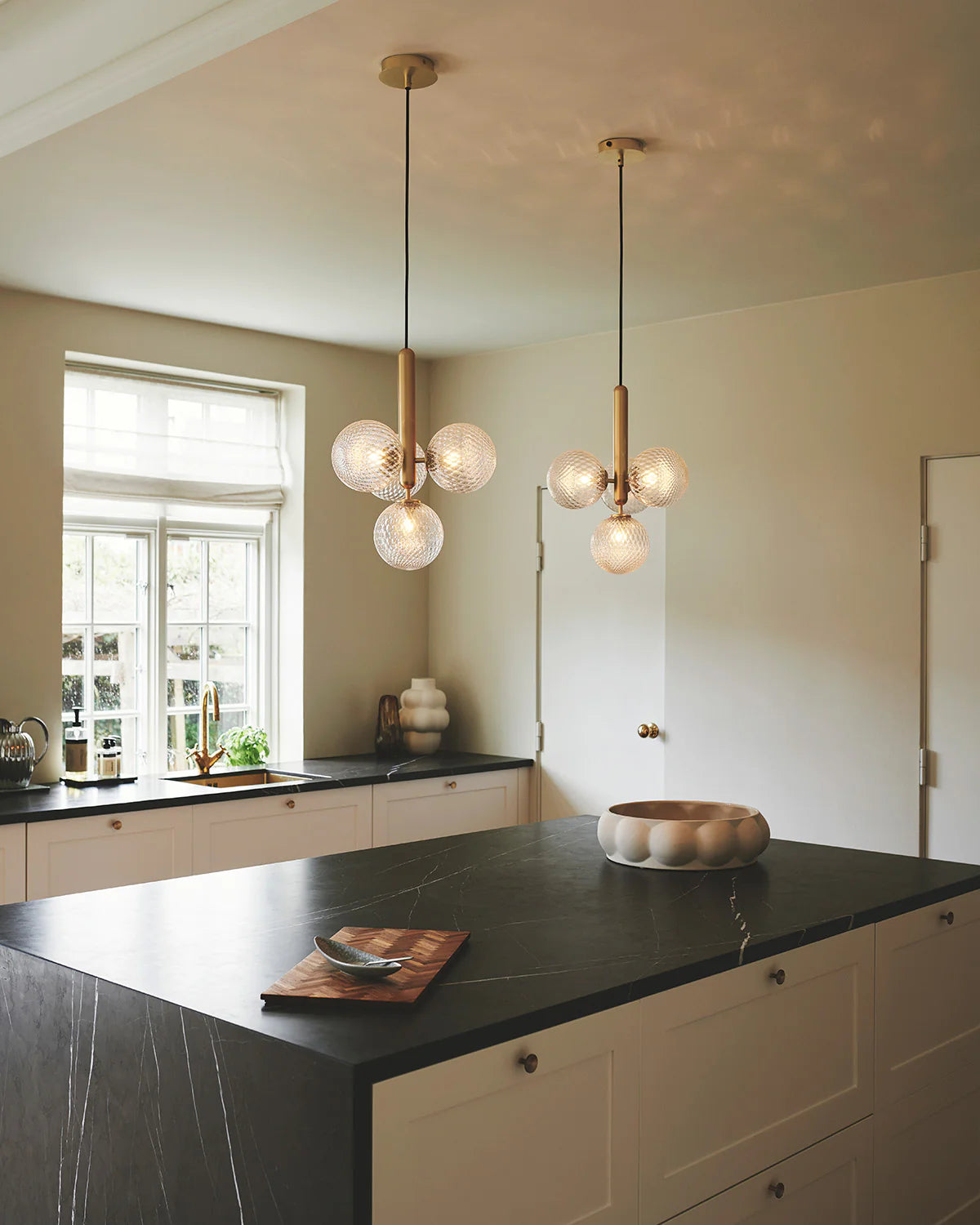 Four-light Scandinavian pendant lamp by Nuura, featuring brass frame and clear glass shades for living room , dining room or kitchen lights