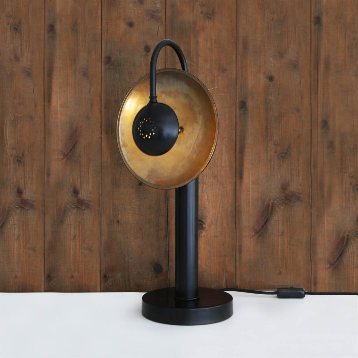 Table lamp with gold and black design against a wooden background